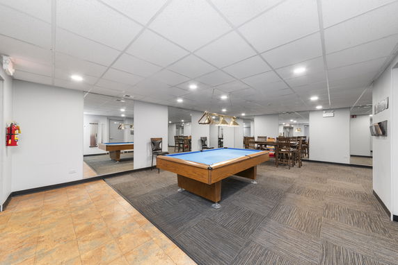 Interior view of a recreational room with pool tables and seating area.