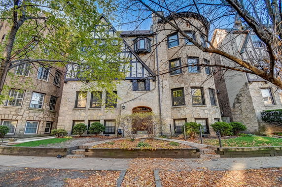 Front view of a multi-story building with stone facade and bay windows.