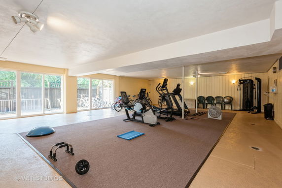 Indoor gym area with exercise equipment and large windows.