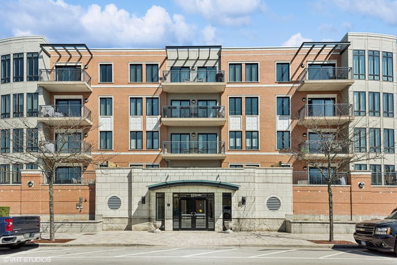 Front view of a multi-story apartment building with balconies and large windows.