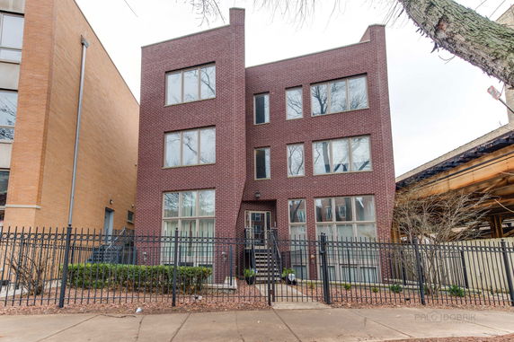 Front view of a three-story brick building with multiple windows and a gated entrance.