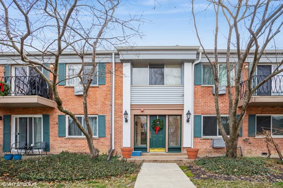 Front view of a two-story brick building with green window shutters and a central entry door.