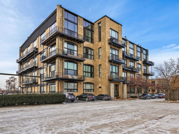 Front view of a multi-story apartment building with balconies and large windows.