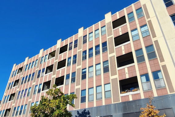 Front view of a multi-story apartment building with a beige and brown facade.