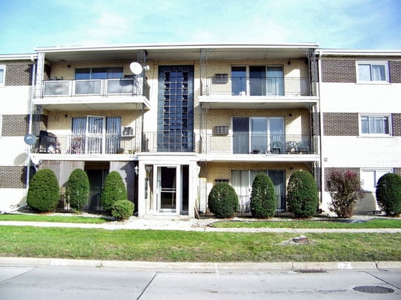 Front view of a multi-story apartment building with balconies.