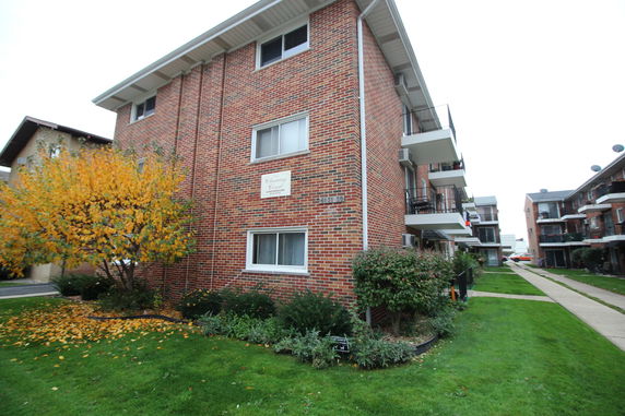Front view of a multi-story brick apartment building with balconies.