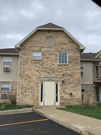 Front view of a multi-story building with brick facade and triangular roof.