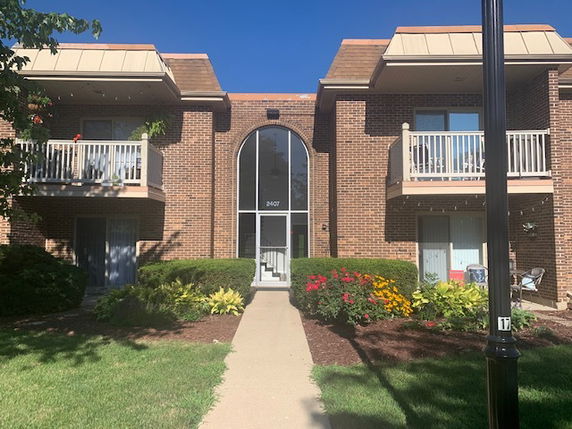 Front view of a two-story brick apartment building with balconies and central entrance.