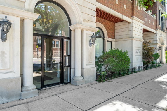 Front view of a building entrance with arched windows and decorative columns.