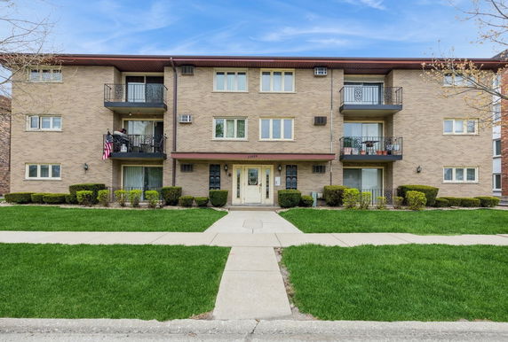Front view of a three-story apartment building with balconies.