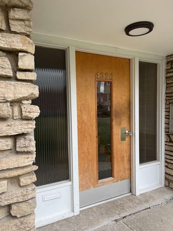 Front view of a house entrance with a wooden door and side glass panels.