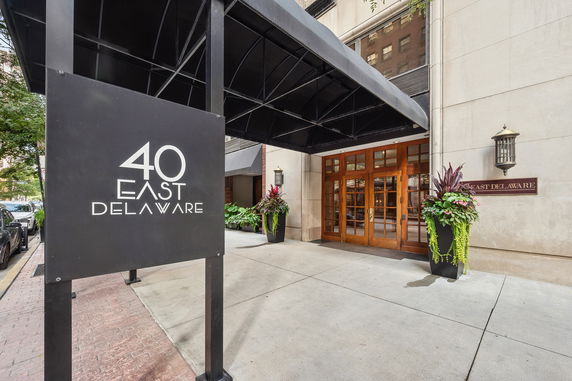 Front entrance of a building with a glass door and canopy, labeled 40 East Delaware.