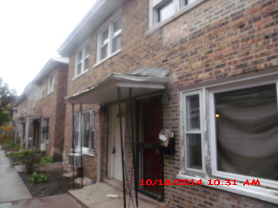 Front view of a multi-story brick building with multiple windows and a small porch.