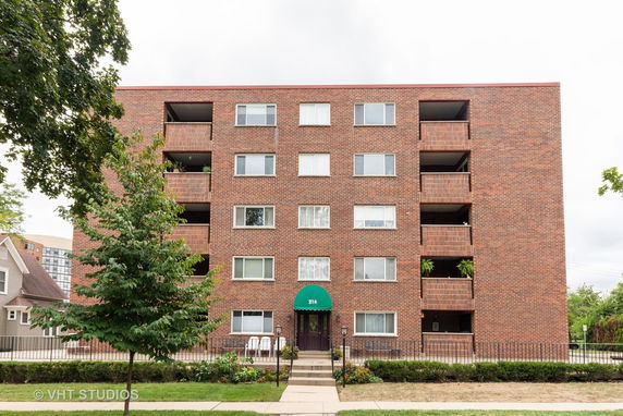 Front view of a multi-story brick apartment building with balconies.