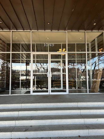 Front view of a building entrance with glass doors and steps.