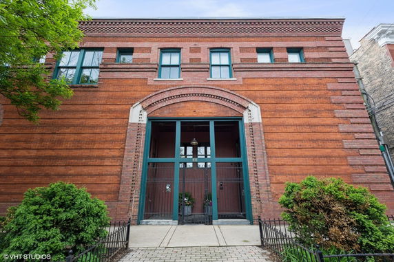 Front view of a red brick building with a large arched entrance and multiple windows on the upper level.