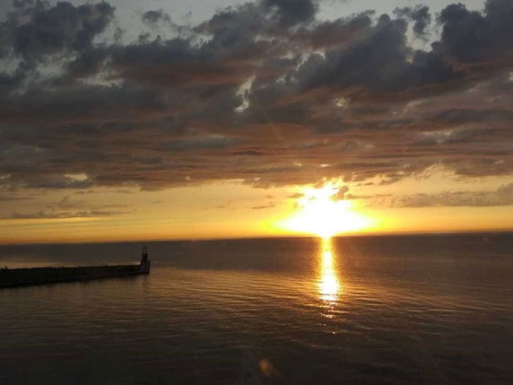 Wide angle view of the sea at sunset with a pier extending into the water.