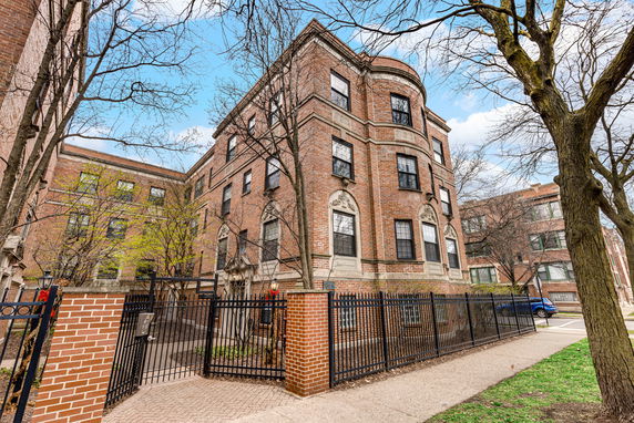 Front view of a multi-story brick building with decorative details and large windows.