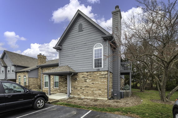 Front view of a two-story house with a brick and gray siding exterior and a balcony.