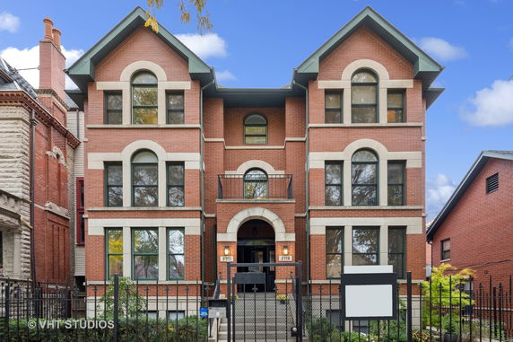 Front view of a multi-story brick house with arched windows and a central balcony.