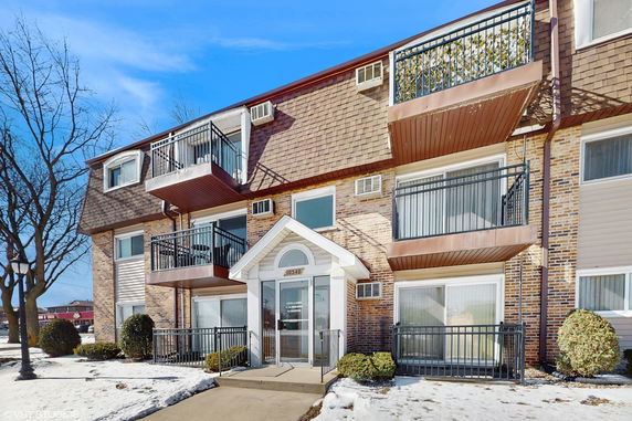 Front view of a multi-story residential building with balconies and brick exterior.