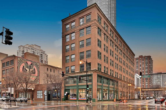 Front view of a multi-story brick building on a city street corner.