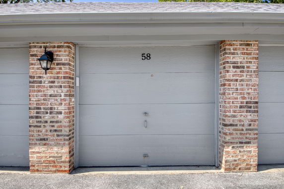 Front view of a garage door with brick columns and a light fixture.