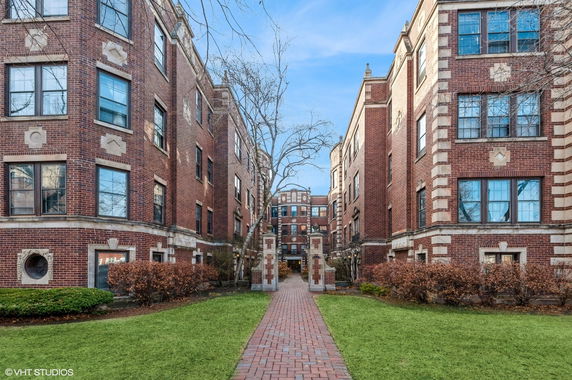 Front view of a brick apartment building with multiple stories and decorative details.