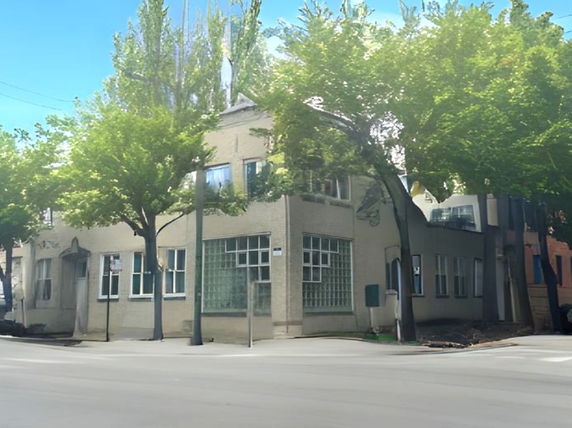 Front view of a two-story building with large windows and trees nearby.
