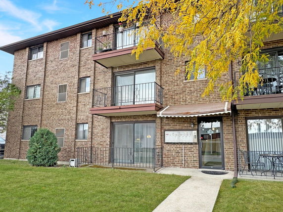 Front view of a multi-story brick apartment building with balconies.
