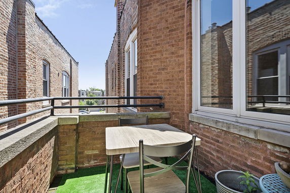 View of surrounding area from a small balcony with a table and chairs.