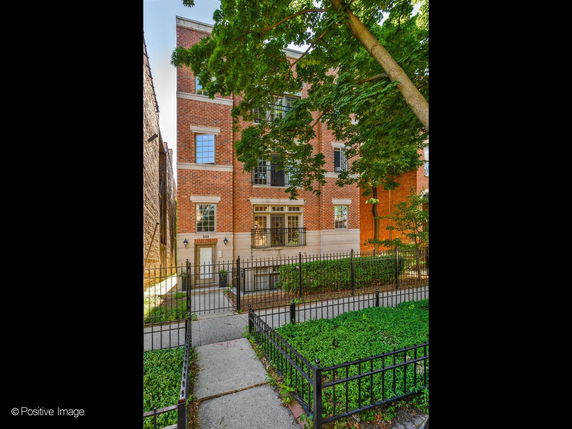 Front view of a multi-story brick building with a fenced entrance.