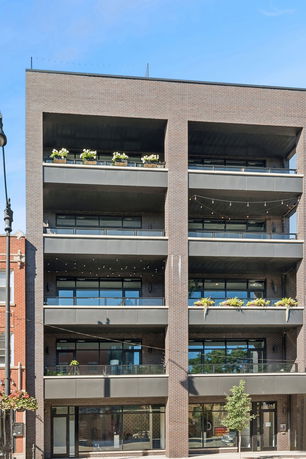 Front view of a multi-story building with balconies and large windows.