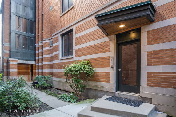 Front view of a brick building entrance with steps and a door overhang.