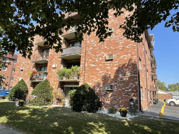 Front view of a multi-story brick apartment building with balconies.