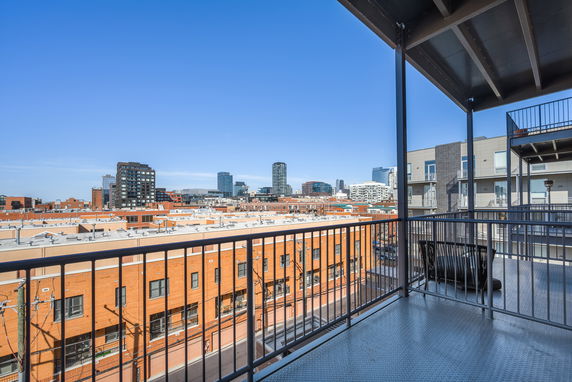Panoramic view from a balcony overlooking city buildings and skyline.