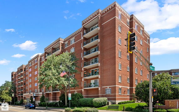Front view of a multi-story red brick apartment building with balconies.