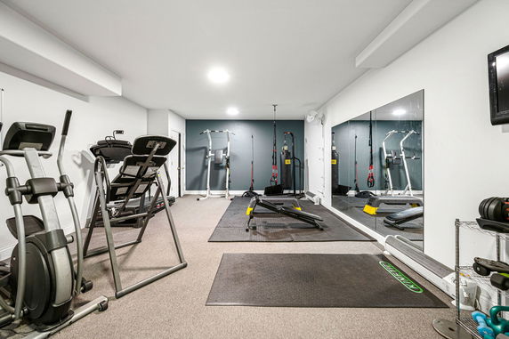 Home gym with various exercise equipment and large mirrors.