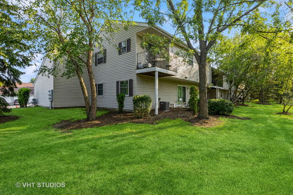Side view of a two-story house with a balcony and sliding doors on the ground floor.
