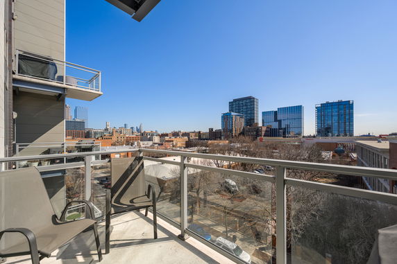 Balcony with chairs offering a cityscape view of buildings.