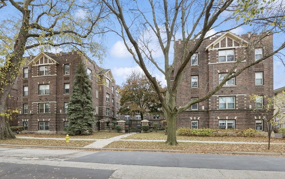 Front view of a brick apartment building with multiple floors and decorative stone elements.