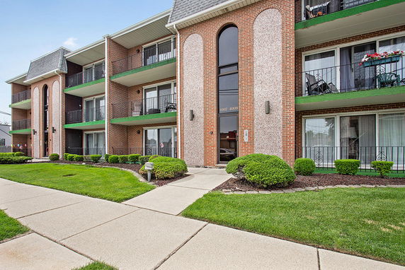 Front view of a multi-story building with balconies and brick facade.