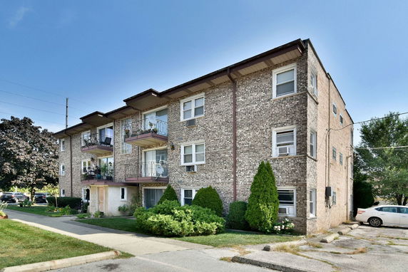 Front view of a three-story brick apartment building with balconies.