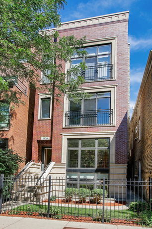 Front view of a multi-story brick building with balconies and large windows.