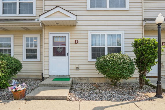 Front view of a two-story townhouse with a white door and beige siding.