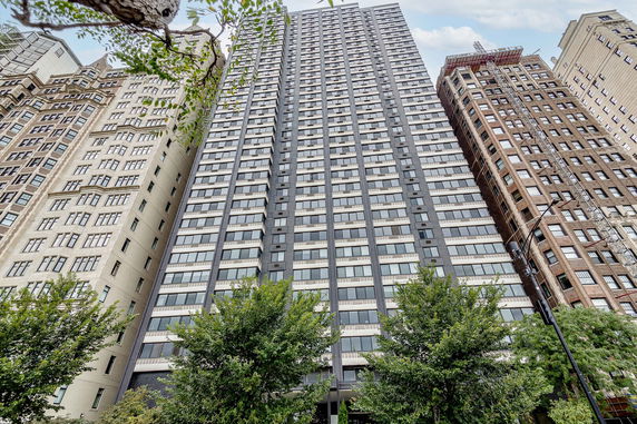 Front view of a tall, modern high-rise building surrounded by other tall buildings.