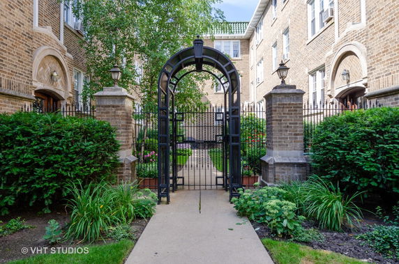 Front view of a multi-story brick building with an arched entrance gate.