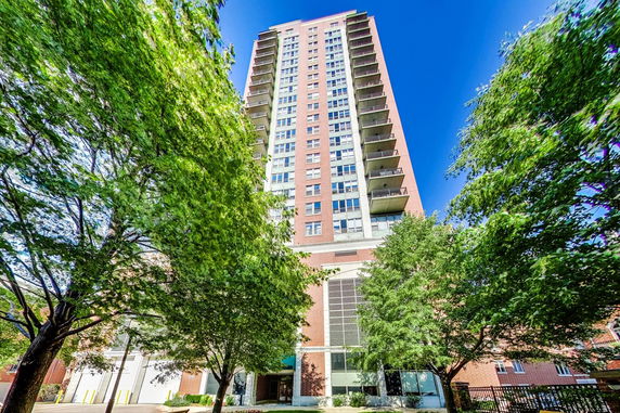 Front view of a tall residential building with multiple balconies.