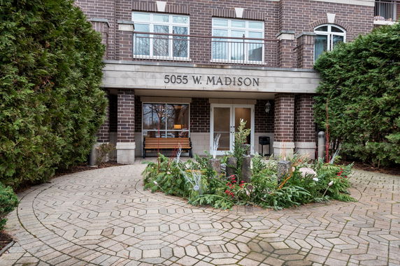 Front view of a multi-story brick building entrance with decorative planters.