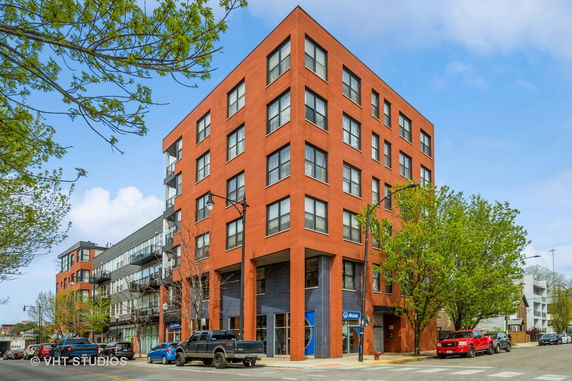Front view of a multi-story brick building with large windows.